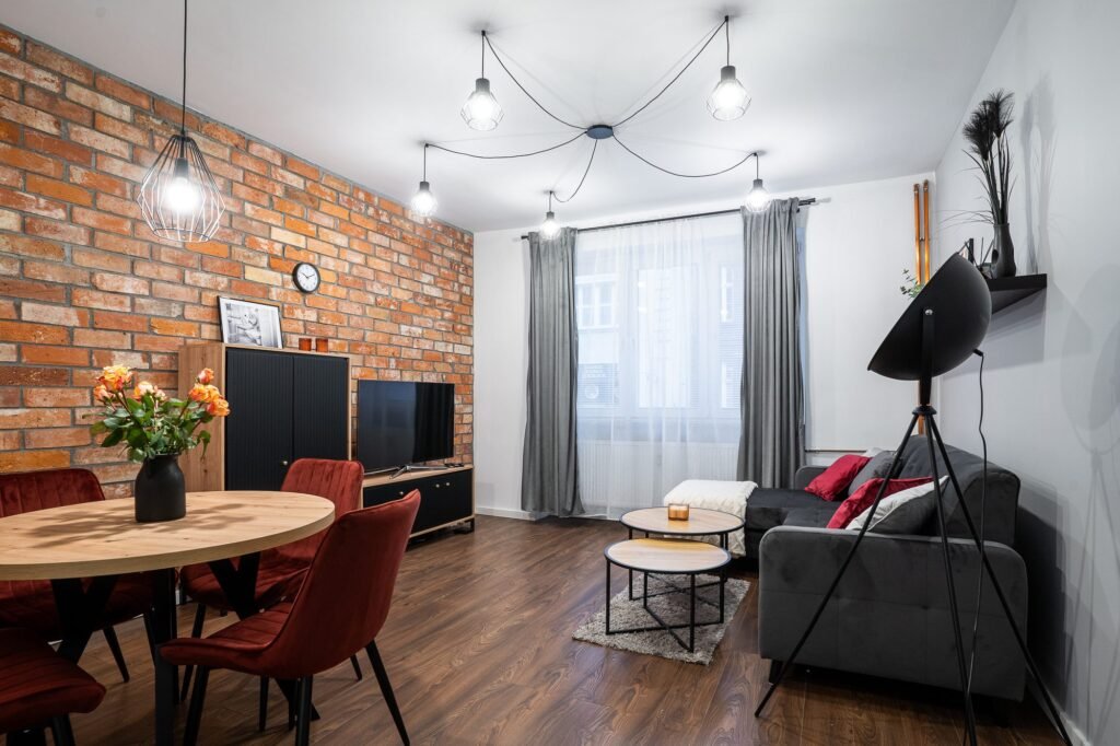 Salon z ceglaną ścianą i strefą jadalni – zdjęcia mieszkania na sprzedaż Poznań